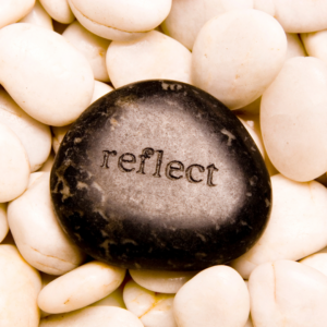 white stones with large black stone engraved with the word Reflect
