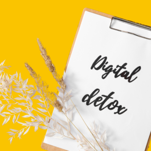 clip board with writing "Digital Detox" decorative dried flower spray lay across on yellow background