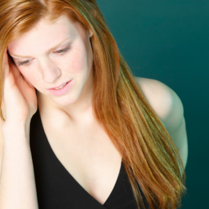 lady with auburn hair looking down with worried expression