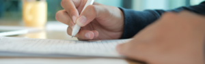 picutre of a female hand holding a pen to fill out an application form