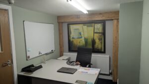 ground floor shared office space for 2 people with desk, white board and abstract picture in background