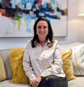 Sharon Louca sat on sofa smiling at the camera