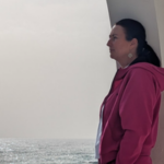 Sharon looking to the side overlooking the sea on a gloomy day